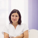 portrait of female dermatologist standing with arms crossed in clinic