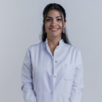 smiling young female doctor wearing medical robe looking at camera isolated on white background with copy space